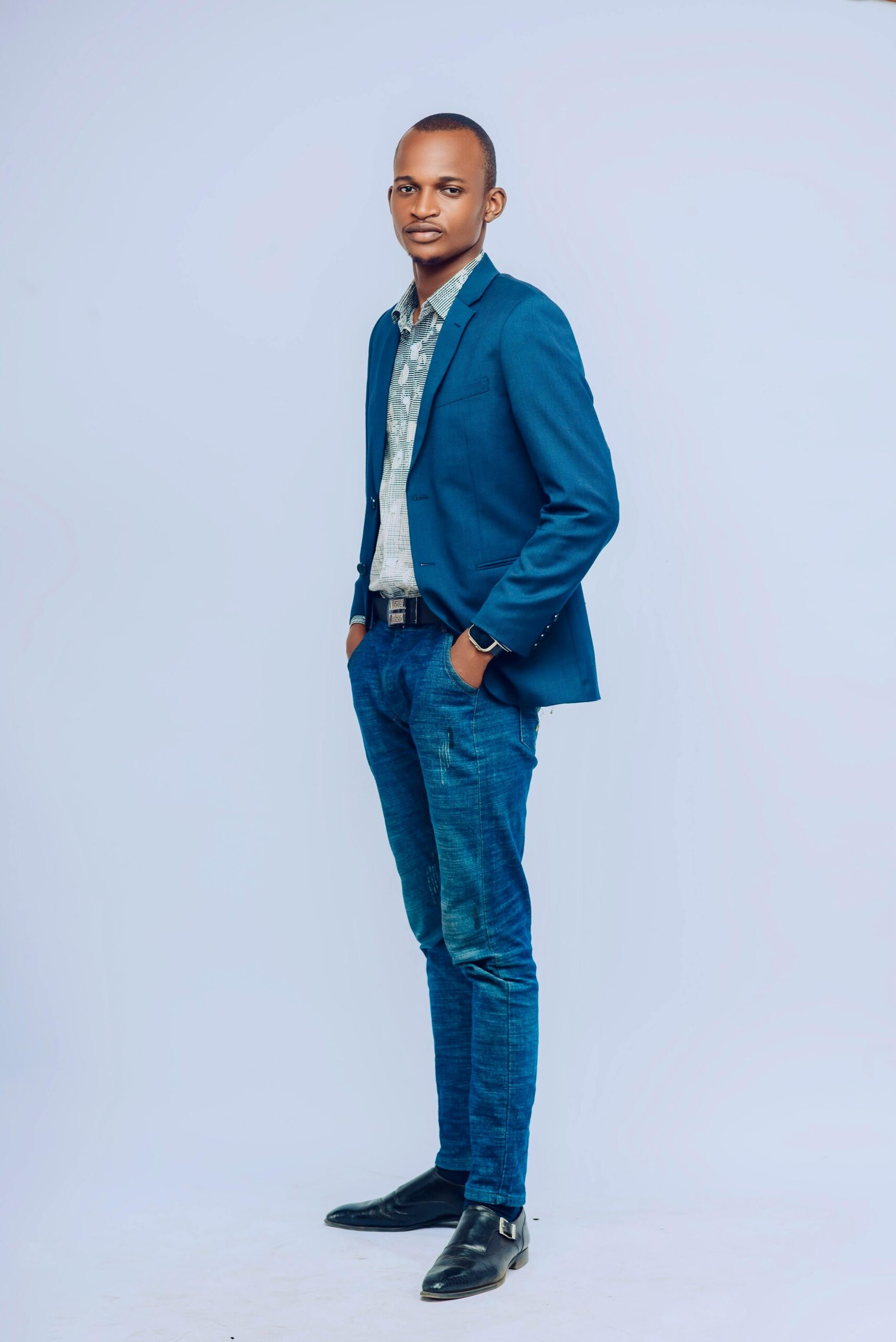 A stylish adult male in blue suit standing confidently against a neutral background.